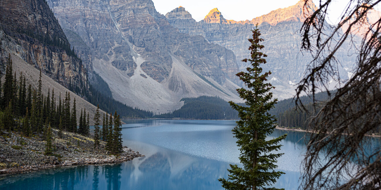 vue sur le lac morraine au lever de soleil. le lac est entouré de montagne majestueuses et de sapins