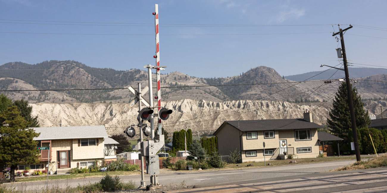 passage à niveau à kamloops avc les montagnes arides en arrière plan. la journée est ensoleillée