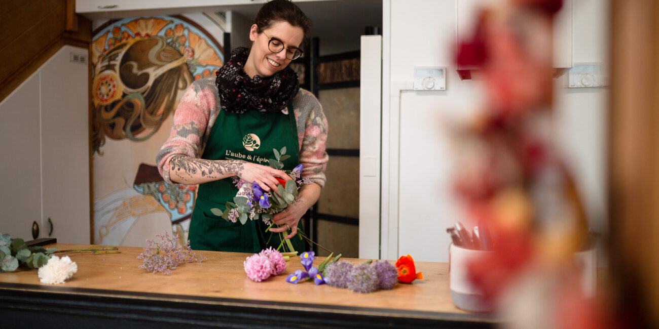 Fleuriste créant un bouquet de fleurs colorées dans l’atelier L’aube & l’épine