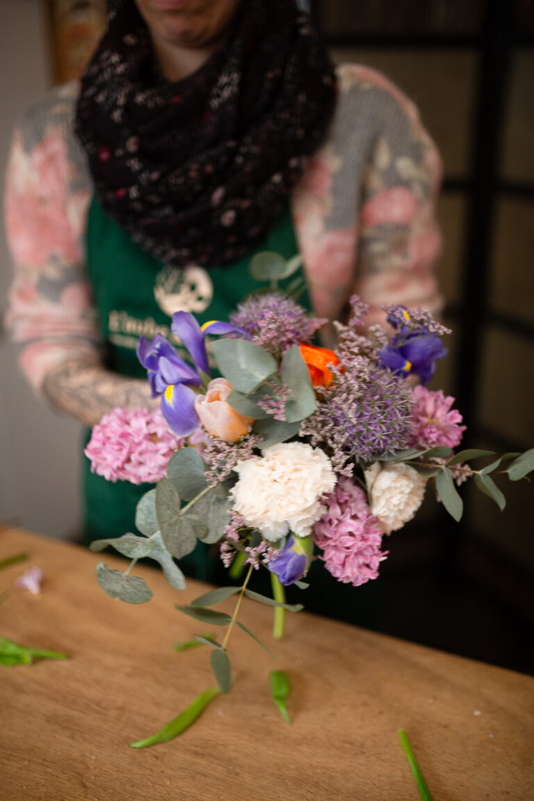 Artisane fleuriste assemblant des fleurs de saison pour un bouquet sur mesure
