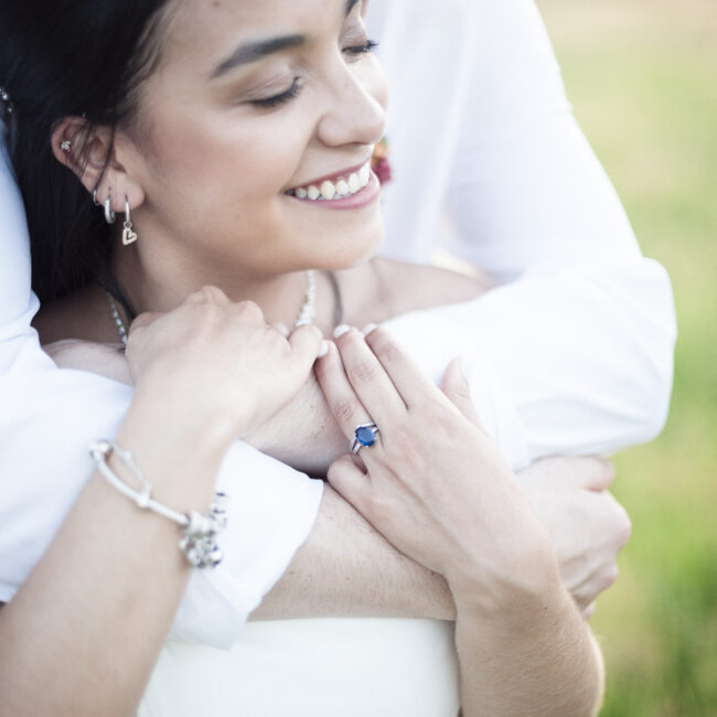 Deux jeunes mariés se prennent dans les bras dans un champ en Alsace, partageant un moment intime et paisible.