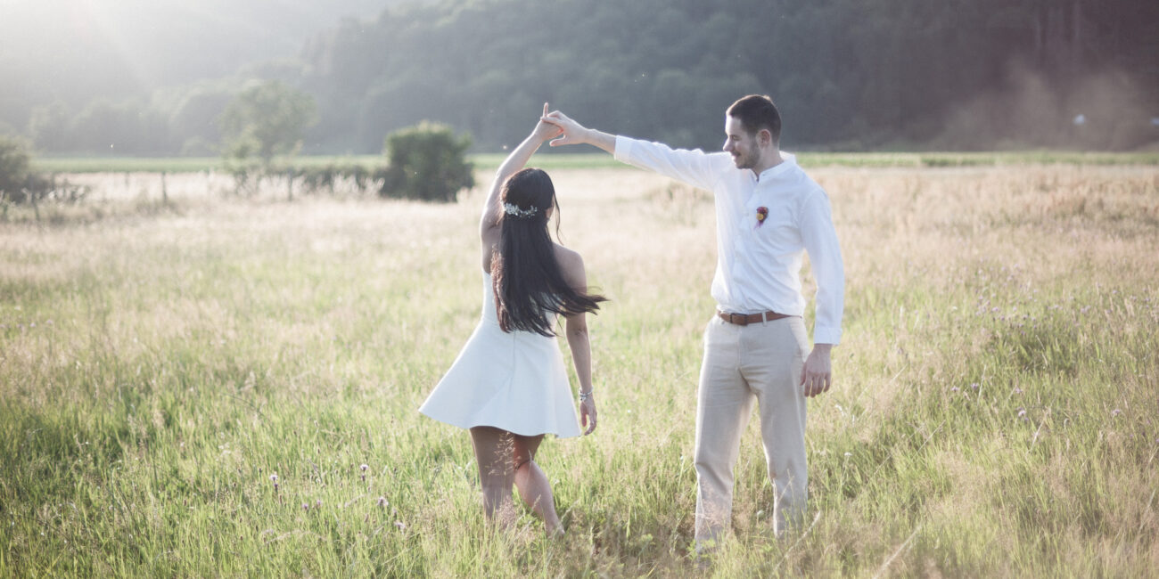des mariés dansant dans un champ de hautes herbes au coucher du soleil, partageant un moment intime et paisible dans les vosges